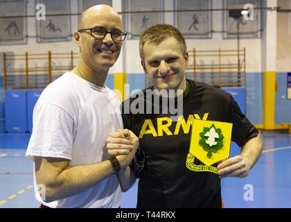 SKWIERZYNA, Polen (Feb. 21, 2019) - Kapitän Jameson Williams ein kaplan von 101 Brigade Support Bataillons, 1st Armored Brigade Combat Team, 1.Infanterie Division, präsentiert 2. Lt Krzysztof Komorek, Executive Officer für die Skwierzyna polnischen Schulungsprogramm, ein handgemachtes Geschenk der Anerkennung nach Ihren freundlichen fustal Spiel mit polnischen Soldaten, hier, 24.02.21. Futsal ist eine Variante des Standard outdoor Fußball, auf einem Hartplatz und in der Regel im Innenbereich gespielt. Stockfoto