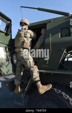 Chief Master Sgt. Chris Simpson, rechts, 18 Air Force command Chief Master Sergeant, sitzt als Soldat aus dem 17 Field Artillery Brigade hebt die einzigartigen Fähigkeiten der High Mobility Artillery Rocket (HIMARS) am Joint Base Lewis-McChord, Wash., Feb 21, 2019. McChord C-17 Globemaster III Flugzeug Transport HIMARS der ländlichen Standorte für realistischere gemeinsame Ausbildung. Stockfoto