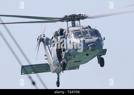 EAST CHINA SEA (Feb. 24, 2019) - Die Crew von einem MH-60S Sea Hawk Hubschrauber vom goldenen Falken von Hubschrauber Meer Combat Squadron (HSC) 12 Ansatz die Landing Zone von US 7 Flotte Flaggschiff USS Blue Ridge (LCC 19). Blue Ridge ist das älteste operative Schiff der Marine, das als 7. Flotte Befehl Schiff, arbeitet aktiv, um Beziehungen mit Verbündeten und Partnern in der indopazifischen Region fördern. Stockfoto