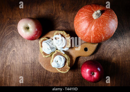 Pfannkuchen mit Sauerrahm, Kürbis und rote Äpfel liegen auf einem Holztisch. top View Stockfoto