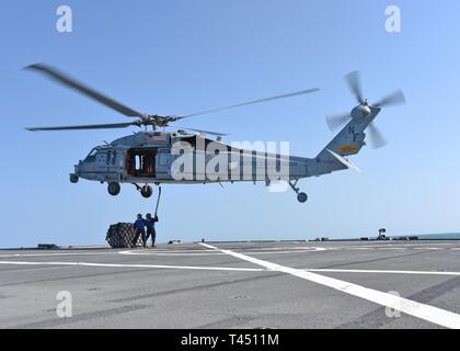 EAST CHINA SEA (Feb. 26, 2019) - der bootsmann Mate 3. Klasse Shawn Bernard, aus Atlanta, Ga. und der bootsmann Mate 3. Klasse Justina Acosta, von Whittier, Kalifornien, befestigen Sie eine Palette von Lieferungen zu einem MH-60S Sea Hawk Hubschrauber vom goldenen Falken von Hubschrauber Meer Combat Squadron (HSC) 12 während einer vertikalen Replenishment (VERTREP) an Bord 7. US-Flotte Flaggschiff USS Blue Ridge (LCC 19). Blue Ridge ist das älteste operative Schiff der Marine, das als 7. Flotte Befehl Schiff, arbeitet aktiv, um Beziehungen mit Verbündeten und Partnern in der indopazifischen Region fördern. Stockfoto