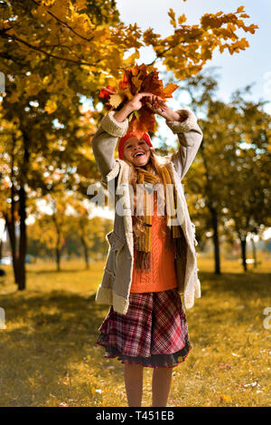 Happy girl in Red Cap springt mit einem Herbst Blumenstrauß der Blätter Stockfoto