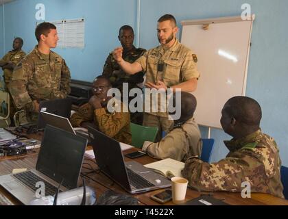 Senior Kapitän Jellen Koch (Mitte), einem belgischen Teilnehmer Flintlock 2019, beschreibt ein Informationen Betrieb best practice mit Partner Kräfte aus den USA, Burkina Faso, Mali, Kamerun, Mauretanien, im Camp Zagre, Burkina Faso, Jan. 26, 2019. Flintlock ist eine jährliche Special Operations und State Department Übung, an der mehr als 2.000 Soldaten, Flieger, Marine- und Polizeikräfte aus 30 nation Kräfte. Lehren aus Flintlock Stärkung der globalen Sicherheit fördern multinationale Institutionen, Austausch von Informationen und die Interoperabilität zwischen westlichen und Partner Nationen entwickeln, Stockfoto