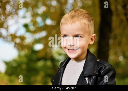 Lustige Portrait von kleinen schlauen Jungen in schwarzem Leder Jacke. Herbst Stockfoto