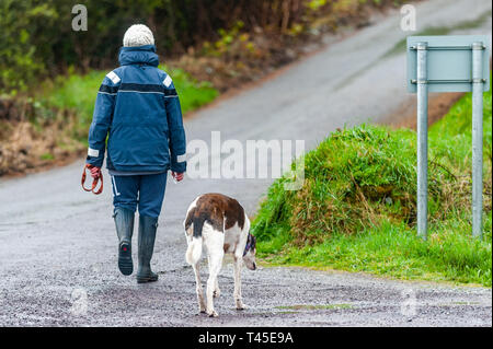 Bantry, West Cork, Irland. 14 Apr, 2019. Eine Frau geht mit ihrem Hund im Regen in Bantry an diesem Nachmittag. County Cork befindet sich mitten in einem Status Gelb Niederschlag und Wind Warnung, die bis 6 Uhr Montag dauert. Credit: Andy Gibson/Alamy Leben Nachrichten. Stockfoto