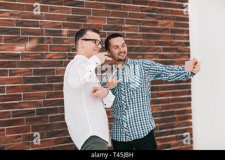 Zwei junge Mitarbeiter unter selfies stehen im Büro. Mensch und Technik Stockfoto