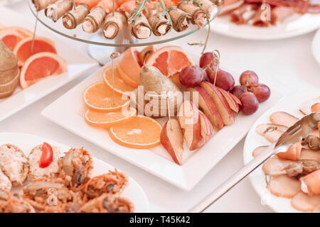 Platte mit Scheiben von verschiedenen Früchten auf dem festlichen Tisch Stockfoto