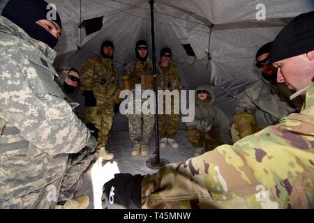 Staff Sgt. Andreas Janka, nördlichen Warfare Training Center Instructor, Gespräche mit Mitgliedern seiner kalten Wetter Führer Kurs 19-004 Squad in der Arktis 10-Mann Zelt am Schwarzen Rapids Training Website März 2 Die Nördliche Warfare Training Center, 2019. Das kalte Wetter Führer Kurs schult Kader- und platoon-Führer in die Kenntnisse und Fähigkeiten, die zur erfolgreichen kleinen unit operations in einer kalten, verschneiten Umgebung durchführen. Schwerpunkt liegt dabei auf den Auswirkungen der Kälte auf Personal und Material, die Nutzung von grundlegenden kaltem Wetter Kleidung und Ausrüstung, winter Bereich Handwerk, Schneeschuh und Ski te Stockfoto