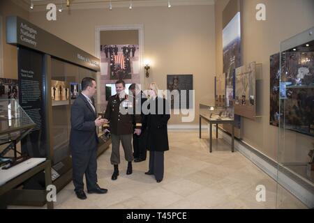 Tim Frank (links), Historiker, Arlington National Cemetery; bietet eine Geschichte Tour zu Generalleutnant M.N. (Mike) Rouleau (Mitte), Commander, Kanadische Joint Operations Command; und sein Partner, Andrea Themely (rechts); in der Gedenkstätte Amphitheater Anzeige Zimmer auf dem Arlington National Cemetery, Arlington, Virginia, 6. März 2019. Während auf dem Friedhof, Rouleau nahmen an einem öffentlichen Wreath-Laying Zeremonie am Grab des Unbekannten Soldaten und beobachtete die Wachablösung. Stockfoto