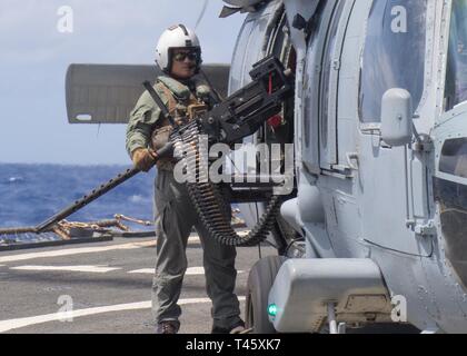 Philippinischen MEER (10. März 2019) einen Seemann, der "Insel der Ritter" Hubschrauber Meer Combat Squadron (HSC) 25, hält eine .50 Kaliber Gewehr außerhalb eines SH-60S Seahawk auf dem Flugdeck der Arleigh-Burke-Klasse geführte-missile Destroyer während des Betriebs im philippinischen Meer.. U.S. Navy Kriegsschiffe Zug zusammen die taktischen Kenntnisse, Letalität zu erhöhen und die Interoperabilität der teilnehmenden Einheiten in einer Zeit, in der Große-Wettbewerb. Stockfoto