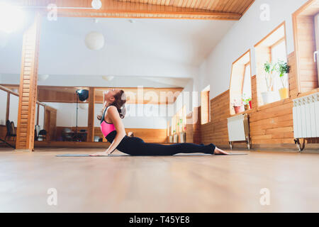 Junge Yogi attraktive Frau yoga Konzept, Stretching in Cobra übung, Bhujangasana darstellen, arbeiten, tragen Sportswear, schwarz Tank Top Stockfoto