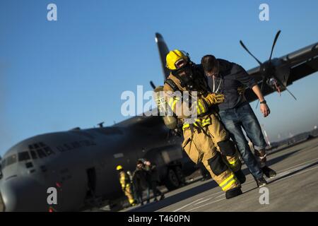 Ein 86Th Bauingenieur Squadron Feuerwehrmann hilft eine simulierte Flugzeugabsturz Opfer während der Übung Operation Varsity 08-07 auf der Air Base Ramstein, Deutschland, Feb.27, 2019. Ramstein für Rettungskräfte wurden auf ihre Fähigkeit, eine große Katastrophe zu reagieren getestet. Stockfoto