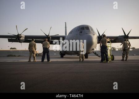 Us-Flieger auf der 75th Expeditionary Airlift Squadron (75 EAS) stehen vor einem C-130J Hercules im Camp Lemonnier, Dschibuti, März zugeordnet. 1, 2019. 75 EAS unterstützt Combined Joint Task Force - Horn von Afrika (CJTF-HOA) mit medizinischen Evakuierungen, Katastrophenhilfe, humanitäre und airdrop Operationen. Stockfoto