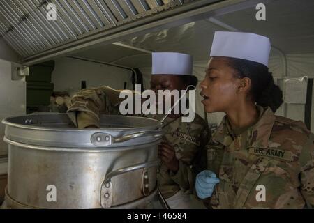 Alaska Army National Guard Pvt. Nyajuok Bol und Pvt. Subria Standifer, Echo Unternehmen, 1.BATAILLON, 207 Aviation Regiment, rühren Chili für den Philip A. Connelly Programm für Exzellenz in der Armee Food Service auf Camp Carroll, Joint Base Elmendorf-Richardson, 2. März 2019. Die Einheit ist im Wettbewerb auf der nationalen Ebene der Connelly-Programm, das eine Armee-weiten Wettbewerb gegen drei andere Mitgliedstaaten. Stockfoto