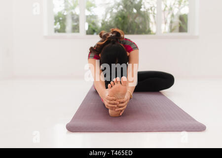 Junge attraktive Yogi frau yoga Konzept, im Janu Sirsasana Übung sitzen, Kopf, Knie nach vorne beugen darstellen, mit schwarzen spo Stockfoto
