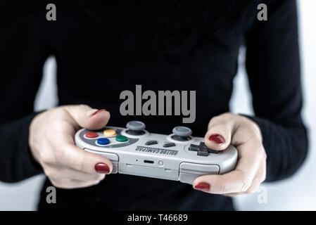 HEGGENES, NORWEGEN - Februar 6, 2019: Nahaufnahme von Frau mit einem Gaming Controller mit Super Nintendo Retro Design spielen Videospiele Stockfoto