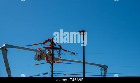 Männer im Eimer auf erweiterten Cherry Picker Instandsetzung der elektrischen Kabel Stockfoto