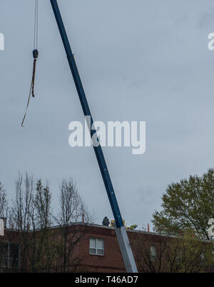 Zwei Arbeiter auf einem Dach mit Gurt hängend von Kran Stockfoto