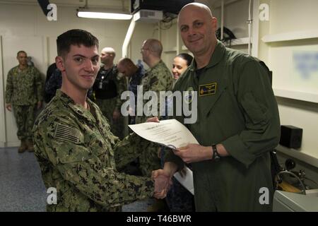 NEWPORT NEWS, Virginia (11. März 2019) Kapitän John J. Cummings, USS Gerald R. Ford's (CVN 78) kommandierenden Offizier, präsentiert die Navy Sicherheitskräfte Sentry Zertifikat der Graduierung zu Airman Lehrling Kristopher West, von Dallas, von Ford's Air Abteilung während einer in-port security Force (ISF) Klasse Graduierung zugeordnet. Ford wird derzeit in post-shakedown Verfügbarkeit Huntington Ingalls Industries-Newport Nachrichten Schiffbau. Stockfoto