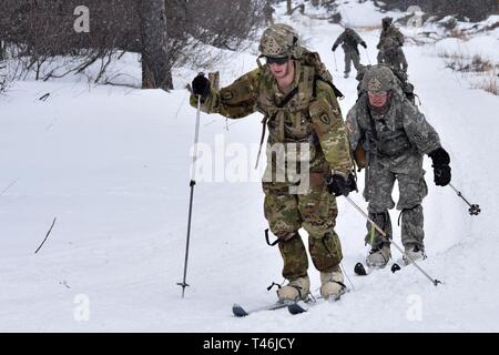 Bei kaltem Wetter Führer Kurs 19-004 Studenten ski entlang Hippie Trail nach dem Feuern Teil des 10 Kilometer langen Biathlon am Schwarzen Rapids Training Website März 12 der Nördlichen Warfare Training Center, 2019. Das kalte Wetter Führer Kurs schult Kader- und platoon-Führer in die Kenntnisse und Fähigkeiten, die zur erfolgreichen kleinen unit operations in einer kalten, verschneiten Umgebung durchführen. Schwerpunkt liegt dabei auf den Auswirkungen der Kälte auf Personal und Material, die Nutzung von grundlegenden kaltem Wetter Kleidung und Ausrüstung, winter Bereich Handwerk, Schneeschuh und Ski Techniken und Winter oder kalten Regionen navigati Stockfoto