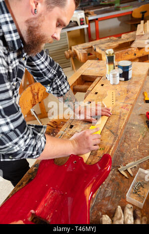 Nahaufnahme eines Handwerkers Schleifen der Gitarrenhals in Holz bei Workshop Stockfoto