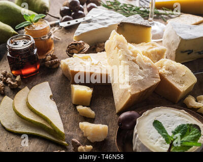 Käseplatte mit Bio Käse, Früchte und Wein auf Holz- Hintergrund. Lecker Käse Starter. Stockfoto