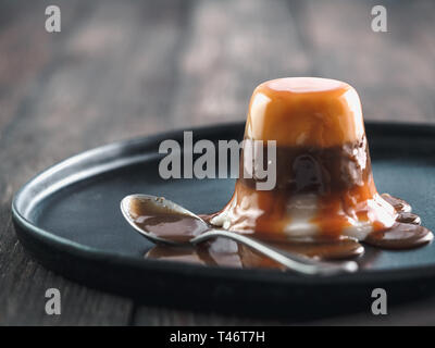 Panna cotta mit Karamellsauce und Schokolade. Italienische dessert Panna cotta auf schwarze Platte, Platz für Text kopieren Stockfoto