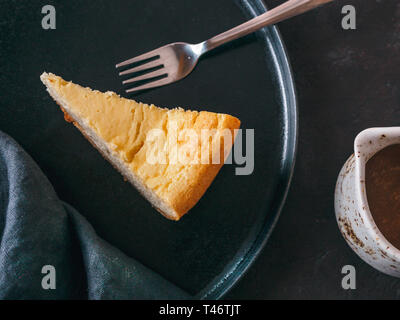 Mit Stück Käsekuchen auf dunklem Hintergrund. Klassische Käsekuchen, Karamellsauce und dessert Gabeln. Top View oder flach. Stockfoto