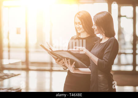Zwei business Frauen lesen Sie die Dokumente im Büro Lobby stehen. Business Konzept Stockfoto