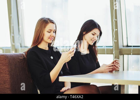 Mitarbeiter können Sie über Ihr Smartphone an einem Tisch in einem Cafe sitzen. Mensch und Technik Stockfoto