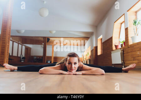 Mädchen in schwarzer Kleidung Yoga. Upavishta Konasana. Inschrift auf Anhänger. Stockfoto