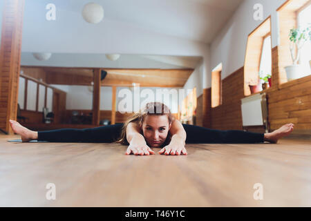 Mädchen in schwarzer Kleidung Yoga. Upavishta Konasana. Inschrift auf Anhänger. Stockfoto