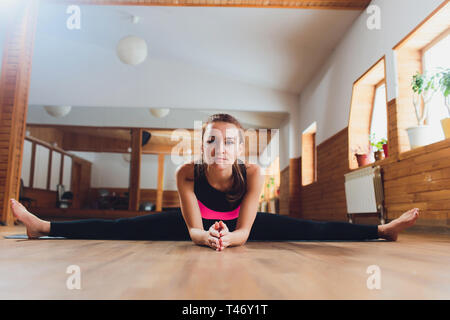 Mädchen in schwarzer Kleidung Yoga. Upavishta Konasana. Inschrift auf Anhänger. Stockfoto