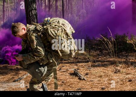 Ein Experte Bereich Medizinische Abzeichen Kandidat erreicht für seine Maske nach einem simulierten chemischer Angriff während Lane Prüfung in Fort Bragg, N.C., 14. März 2019. Soldaten, die Teilnahme am Wettbewerb muss Don Gasmasken innerhalb von neun Sekunden in der Qualifikation für die Armee besondere Fähigkeiten, Abzeichen, um fortzufahren. Stockfoto