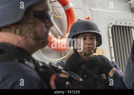 Indischer Ozean (14. März 2019) US-Marine Operations Specialist 2. Klasse Jasmin Bencid, aus Miami, hört sie einen Sicherheit kurze und bohren Spaziergang durch vor der Ausführung besuchen Sie Suche und Seizer (VBSS) Bohrer an Bord der Arleigh-Burke-Klasse geführte Anti-raketen-Zerstörer USS Preble (DDG88). Preble ist in die USA 7 Flotte Bereich für Maßnahmen zur Erhöhung der Sicherheit und Stabilität in der indopazifischen Region bereitgestellt. Stockfoto