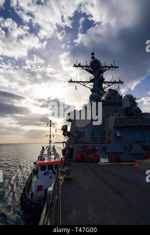 190412-N-QR 145-040 NAVAL SUPPORT ACTIVITY Souda Bay, Griechenland (12. April 2019) - ein schubschiff hilft der Arleigh-Burke-Klasse geführte Anti-raketen-Zerstörer USS Ross (DDG71) an Naval Support Activity Souda Bay, Griechenland, April 12, 2019 ankommen. Ross, Vorwärts - Rota, Spanien eingesetzt, ist auf seine achte Patrouille in den USA 6 Flotte Bereich der Maßnahmen zur Unterstützung der US-amerikanischen nationalen Sicherheitsinteressen in Europa und in Afrika. (U.S. Marine Foto von Mass Communication Specialist 2. Klasse Krystina Coffey/Freigegeben) Stockfoto