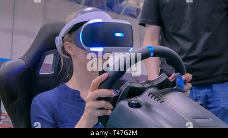 Junge Frau mit Virtual reality Headset und Spielen im Auto Simulator Stockfoto