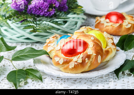 Schöne traditionelle Ostern Brötchen mit Eiern, Mandeln Blütenblätter und zitronenschale eingerichtet. Süße festliches Brot in Form von vogelnestern. Selektiver Fokus Stockfoto