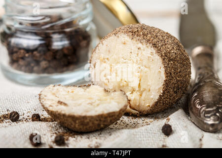 Delikatesse runde kleine Käse mit schwarzem Pfeffer und Knoblauch. Belper Knolle. Würzige Vorspeise für Gourmets. Selektiver Fokus Stockfoto