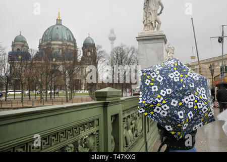 Touristische mit Regenschirm auf dem Weg zur Kathedrale oder den Berliner Dom und Fernsehturm oder Fernsehturm, Berlin, Deutschland. Stockfoto