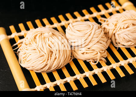 Asiatische Lebensmittel Konzept hausgemachte uncook orientalische Eiernudeln auf Bambus tablett mit Kopie Raum Stockfoto