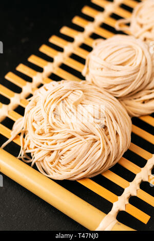 Asiatische Lebensmittel Konzept hausgemachte uncook orientalische Eiernudeln auf Bambus tablett mit Kopie Raum Stockfoto
