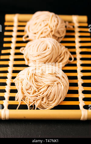 Asiatische Lebensmittel Konzept hausgemachte uncook orientalische Eiernudeln auf Bambus tablett mit Kopie Raum Stockfoto