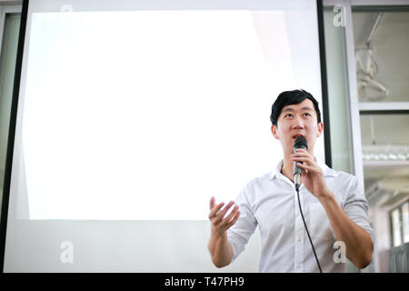Porträt der jungen Hübschen asiatischen Sprecher männlich öffentlich sprechen auf der Bühne Gruppe von Publikum mit White Board hinter Stockfoto