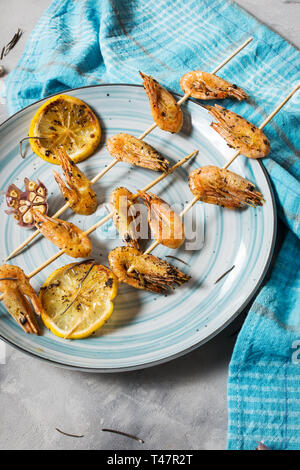 Gegrillte Garnelen Spieße mit Kräutern, Knoblauch und Zitrone auf konkreten Hintergrund. Meeresfrüchte, shelfish. Stockfoto