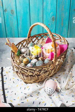 Korb mit Ostern Kuchen und bemalte Eier auf konkreten Hintergrund. Ostern Konzept Stockfoto