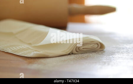 Nahaufnahme des hausgemachten Gebäck auf fillo bemehlten Tisch isoliert. Rolling Pin auf unscharfen Hintergrund Stockfoto