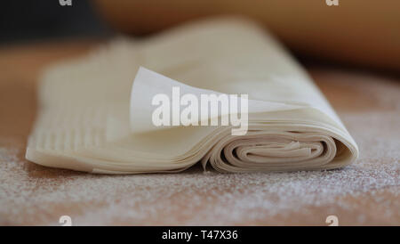 Nahaufnahme des hausgemachten Gebäck auf fillo bemehlten Tisch isoliert. Rolling Pin auf unscharfen Hintergrund Stockfoto