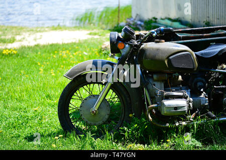 Die sowjetische Dnepr Motorrad auf dem grünen Rasen des vorderen Teil schließen sich gegen einen Sandstrand am See Stockfoto