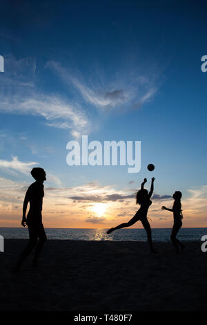 Gruppe von Jugendlichen spielen Volleyball am Strand bei Sonnenuntergang Stockfoto